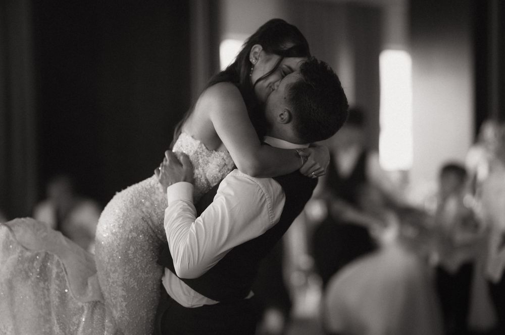 Black and white photo of bride and groom sharing romantic first dance embrace at wedding reception.
