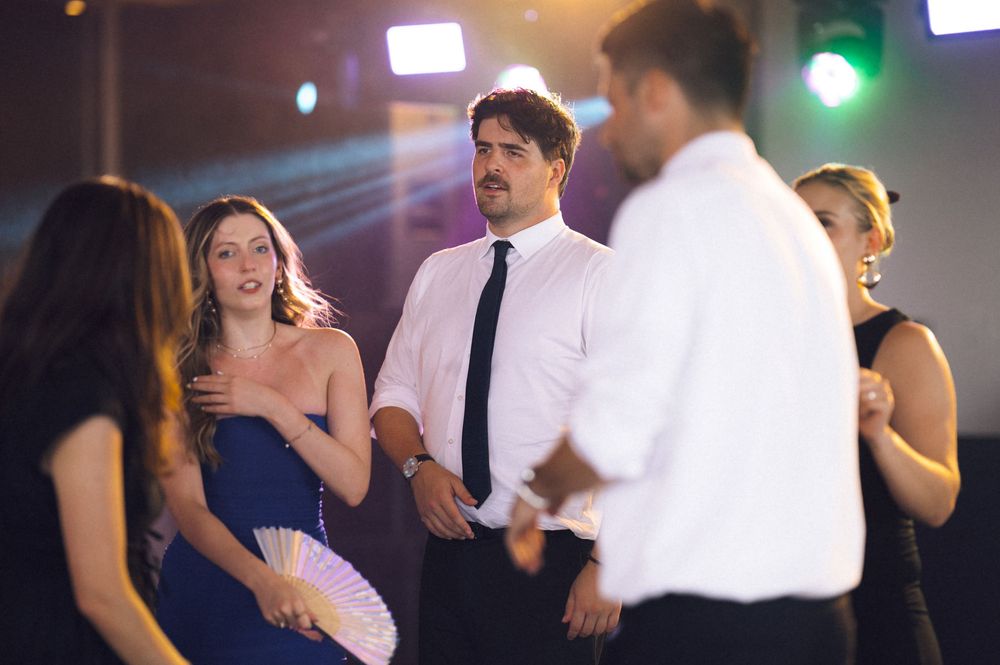Elegantly dressed guests socializing at a formal event, with a woman in blue holding a white fan.
