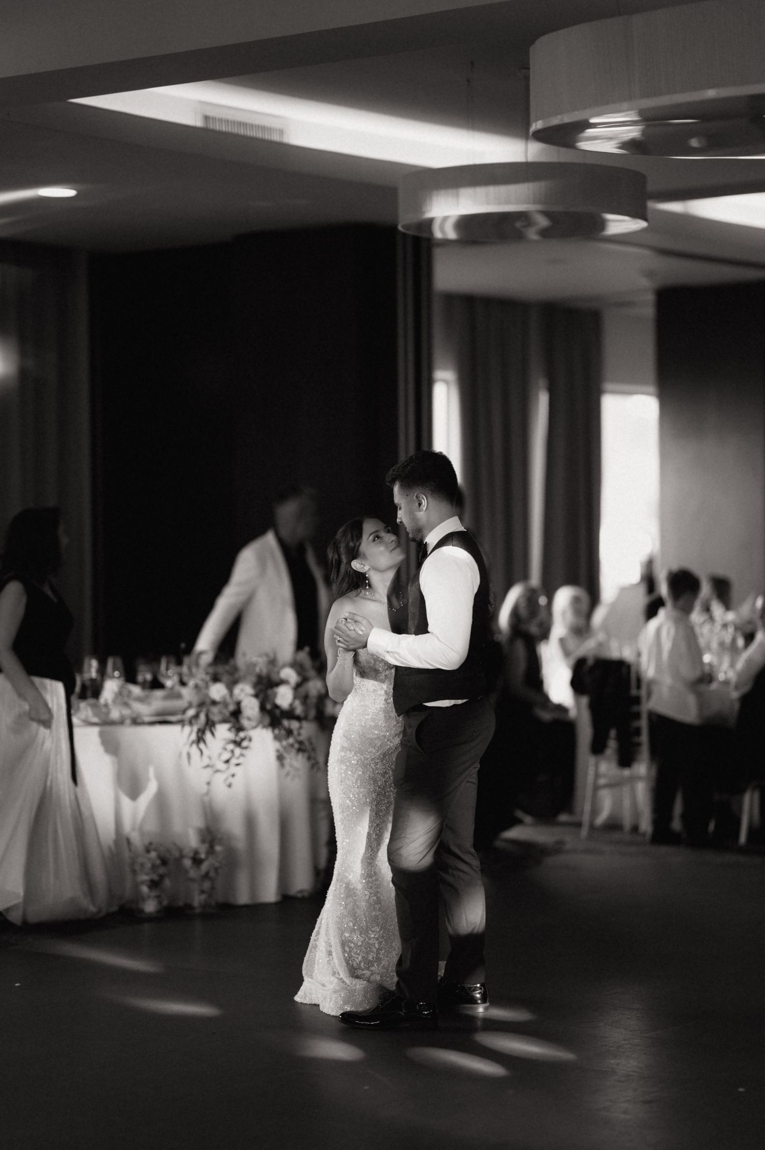 Black and white photo of a bride and groom sharing their first dance at a wedding reception.