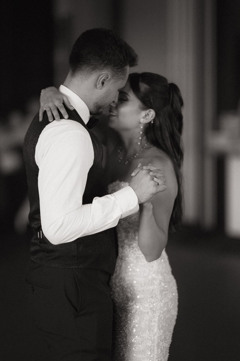 Black and white photo of a couple sharing a romantic first dance at their wedding reception.