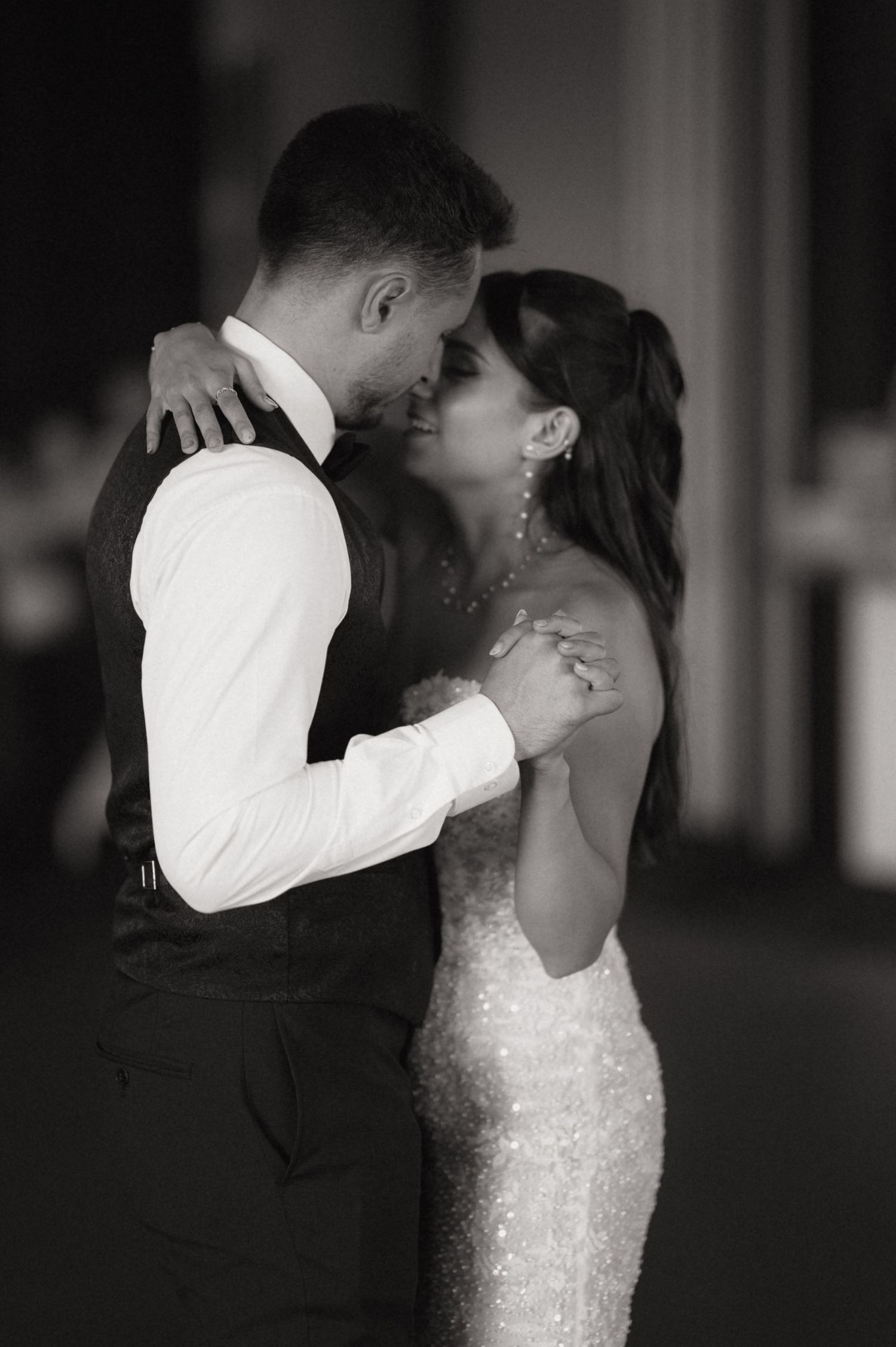 Black and white photo of a couple sharing a romantic first dance at their wedding reception.