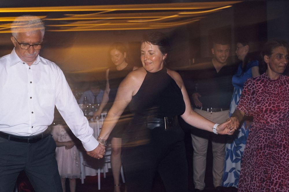 Group of adults holding hands and dancing together at an indoor evening event or celebration.