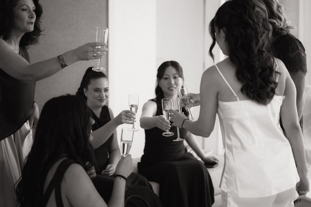 Women toasting with champagne glasses at a wedding celebration in black and white photo.