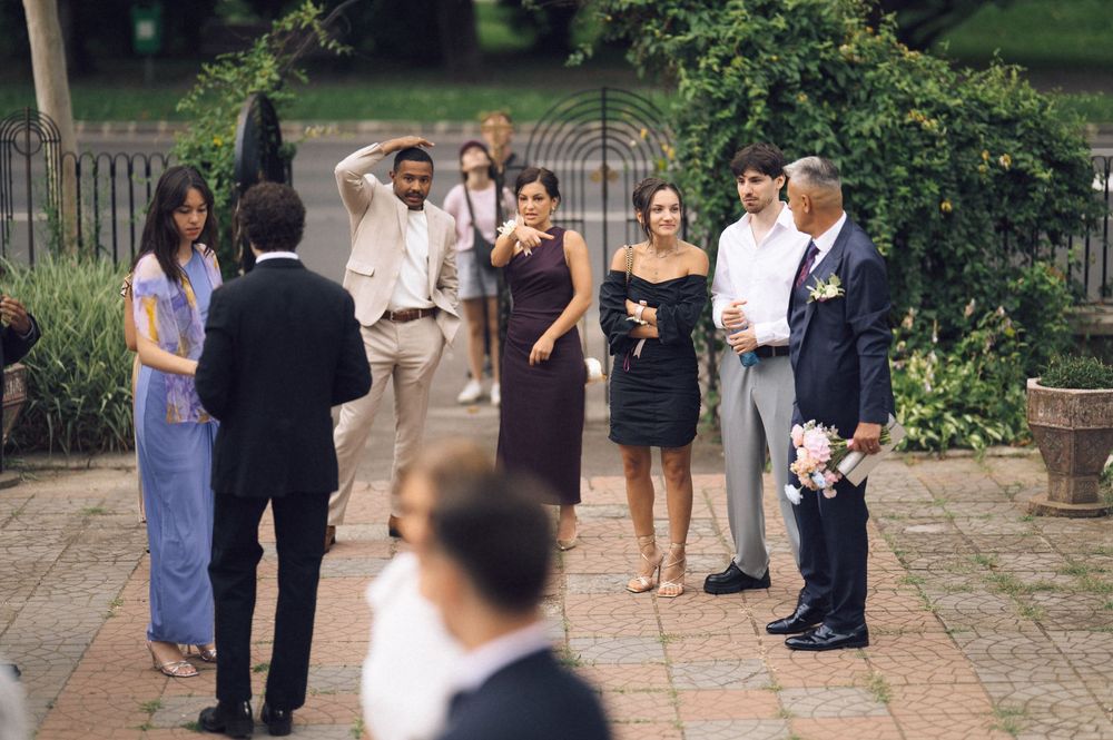 Elegant outdoor wedding reception with guests gathered on a stone patio surrounded by lush greenery.