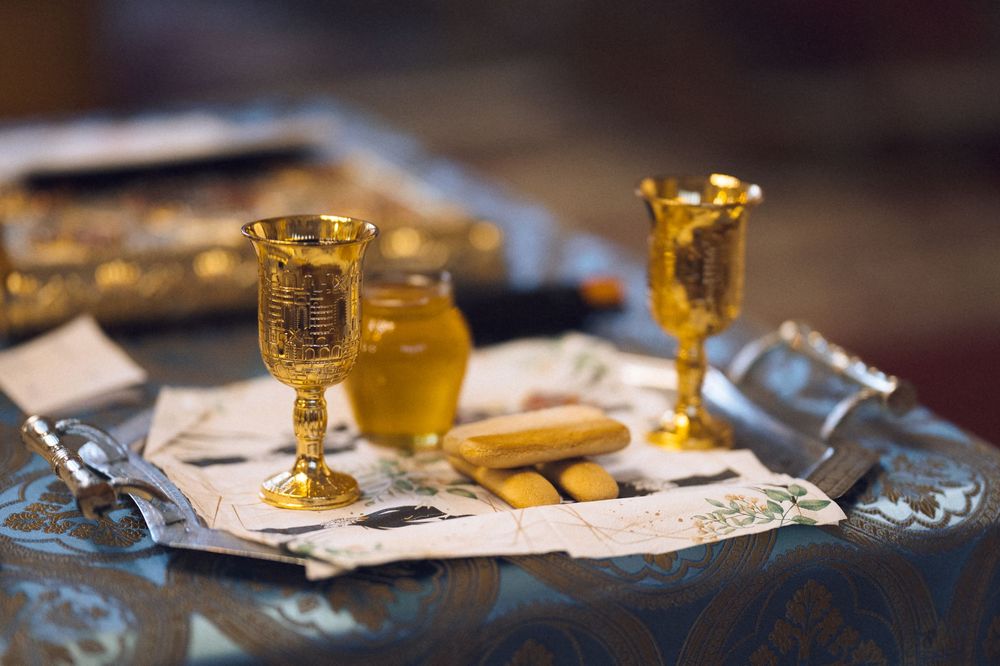 Gold ornate chalices and communion elements arranged on a decorative cloth altar table in a church.