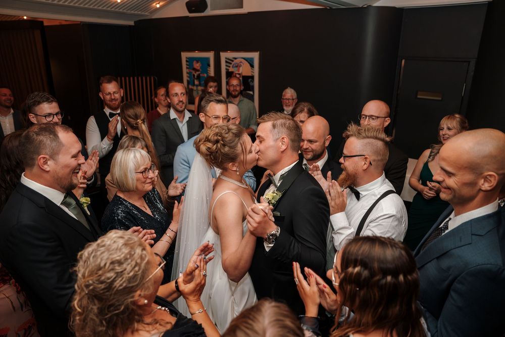 Couple shares an intimate dance moment surrounded by guests applauding at evening wedding reception.
