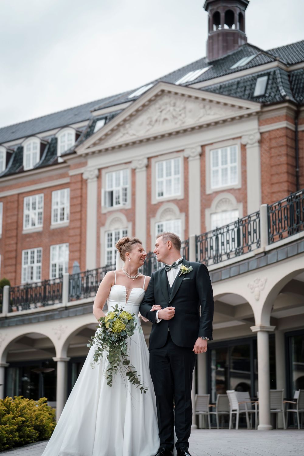 A grand historic building with classical columns and mansard roof serves as an elegant backdrop.