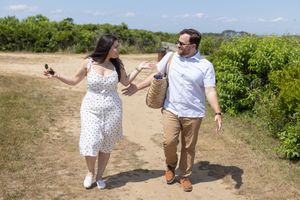 Happy couple walking on a sunny nature trail, woman showing off new engagement ring.