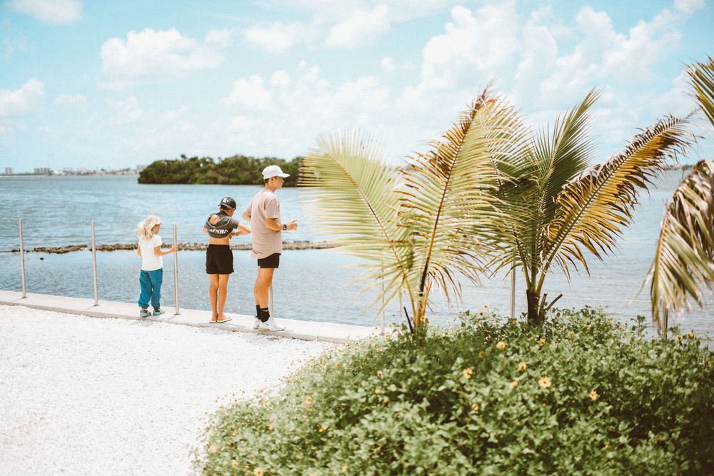 Family enjoying a scenic waterfront walk near tropical palm trees on a sunny day at a Florida Keys beach.