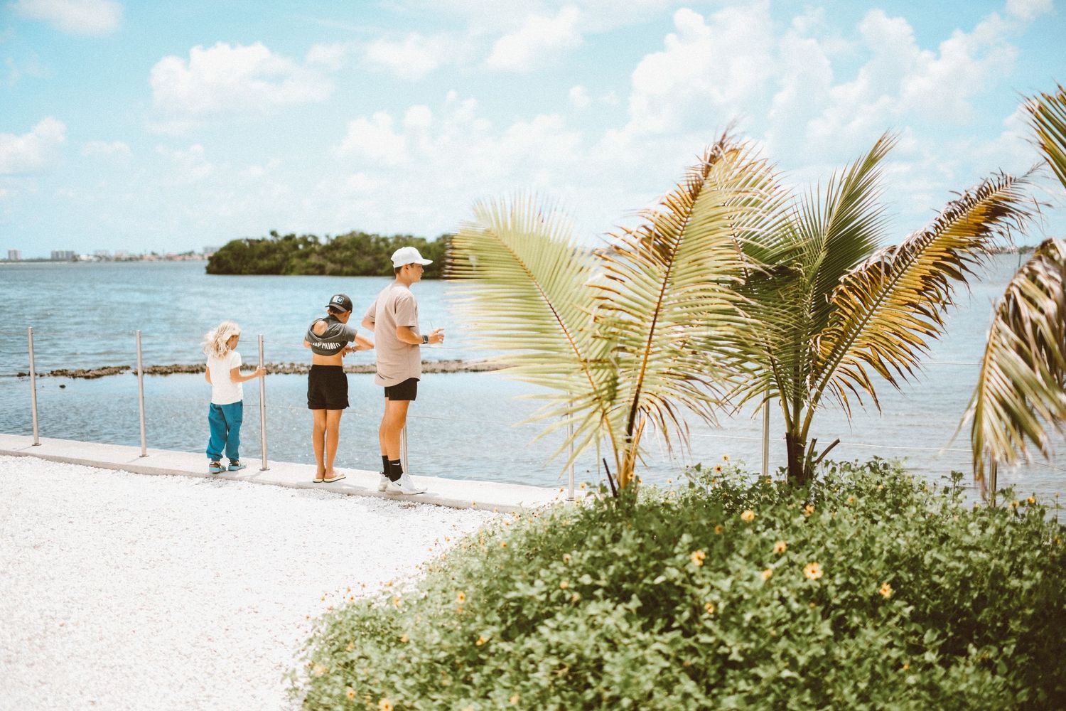 Family enjoying a scenic waterfront walk near tropical palm trees on a sunny day at a Florida Keys beach.
