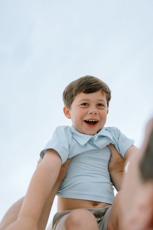 Baby boy being lifted in the air by his dad on the beach in Gulf shores and Orange beach.
