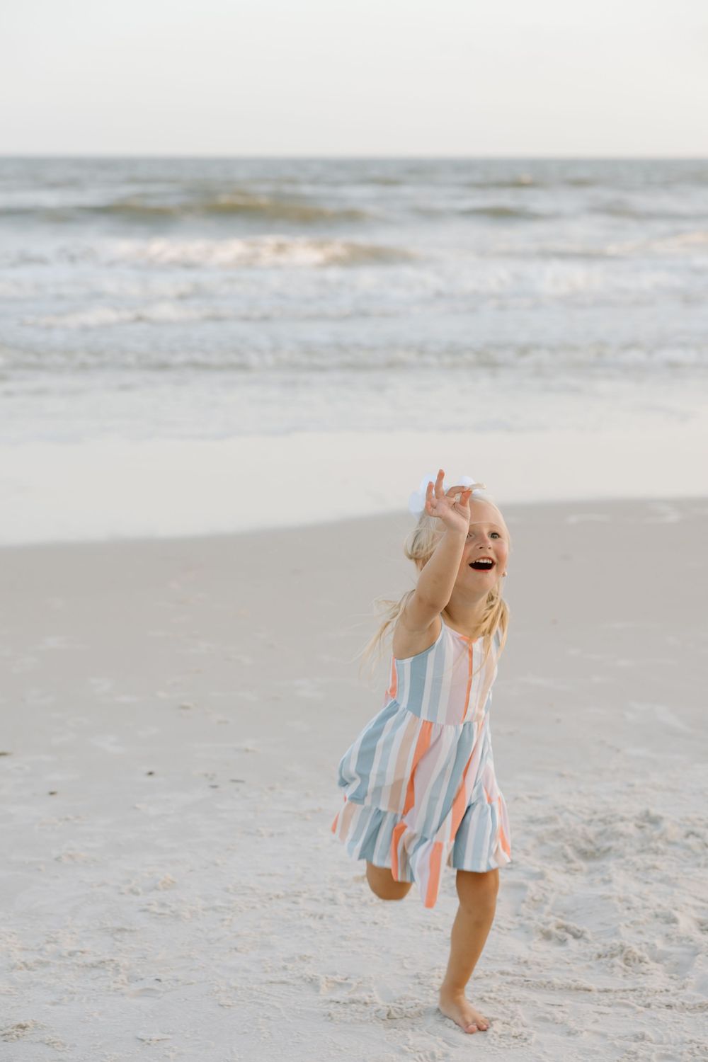 Toddler girl picking up seashells on the beach in Gulf shores and Orange beach.