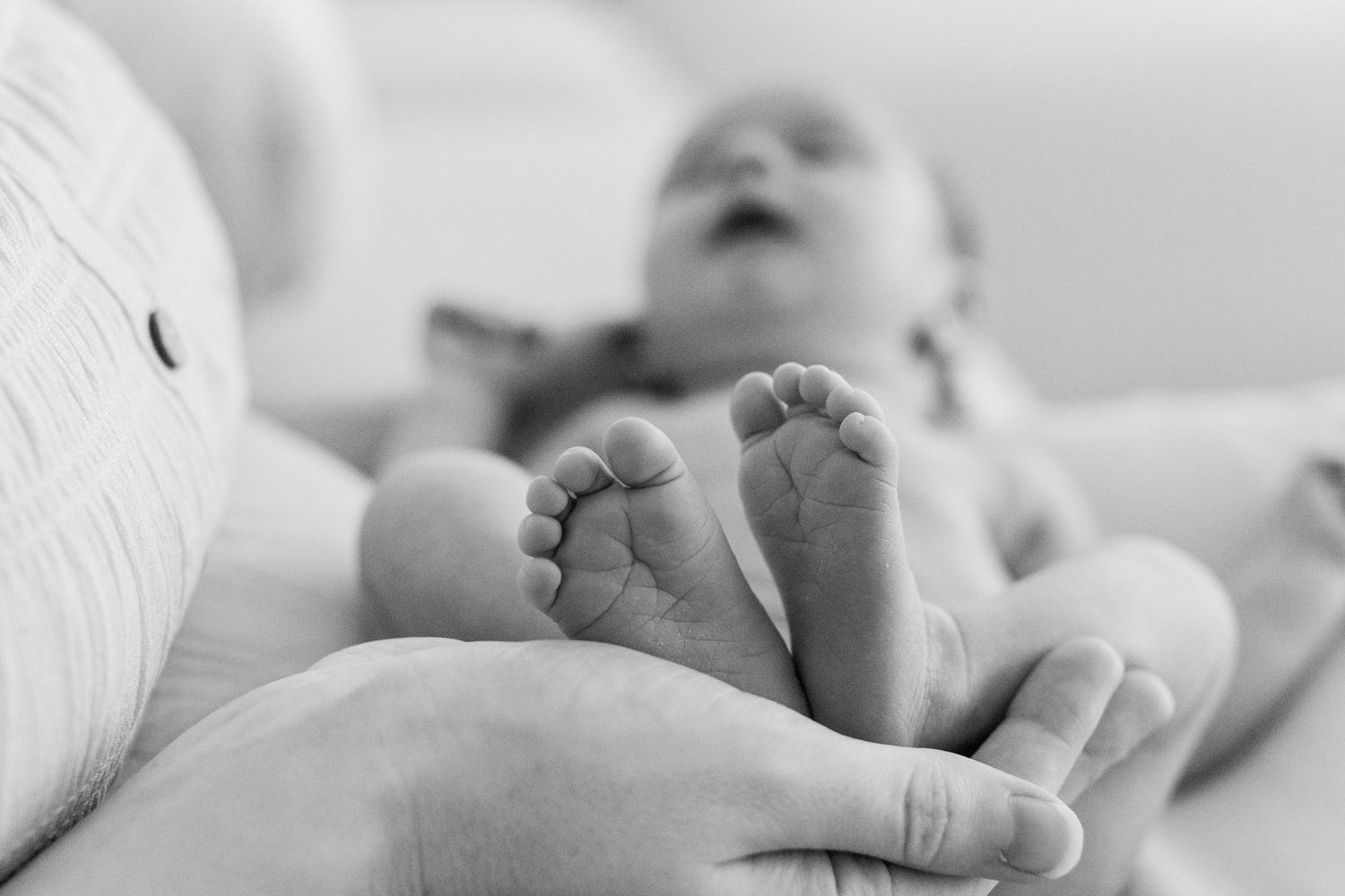 Black-and-white portrait of a newborn, focusing on her feet. In-home lifestyle newborn session in Guaynabo, Puerto Rico.