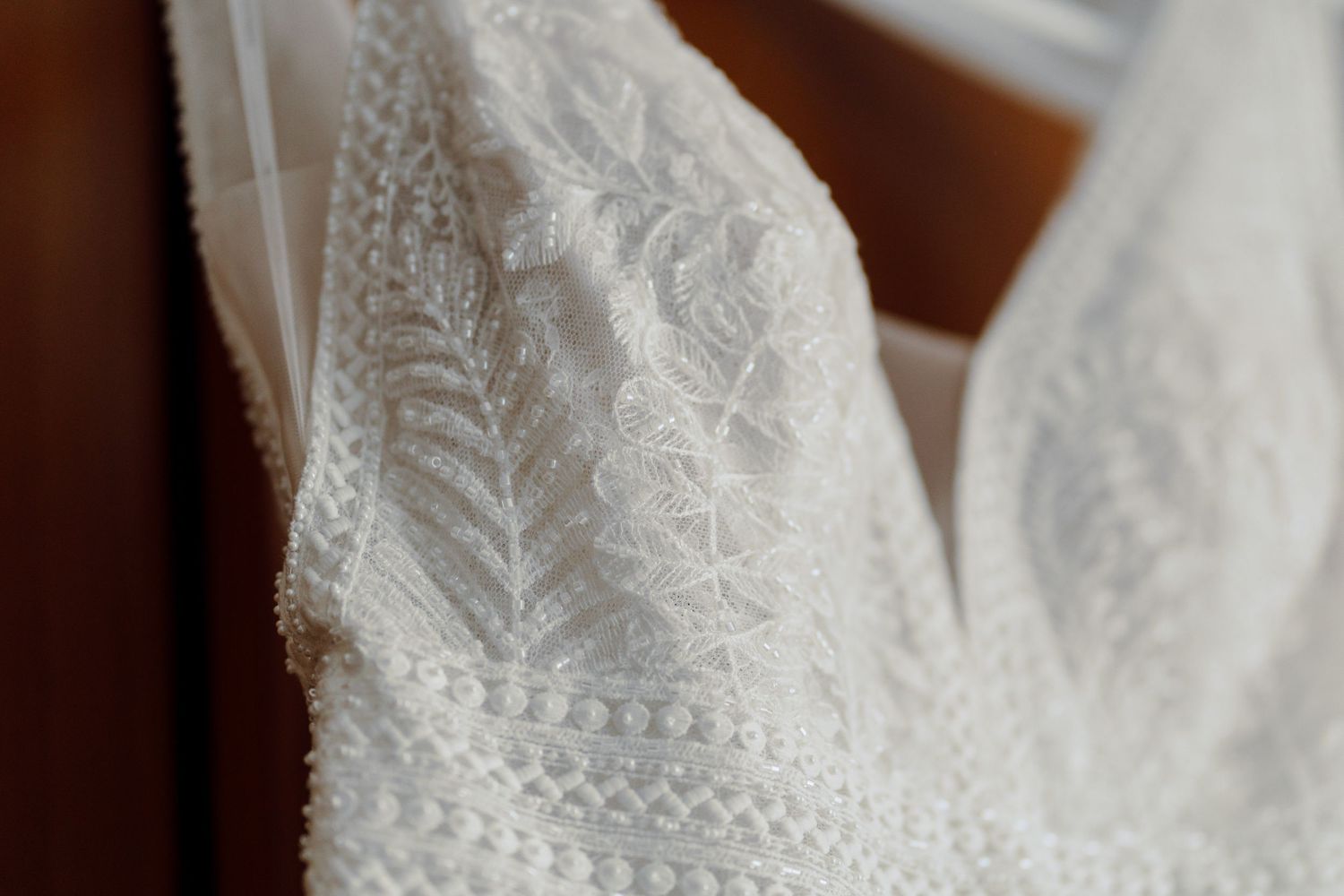 Close-up of intricate white lace embroidery with delicate leaf patterns on an elegant wedding dress.