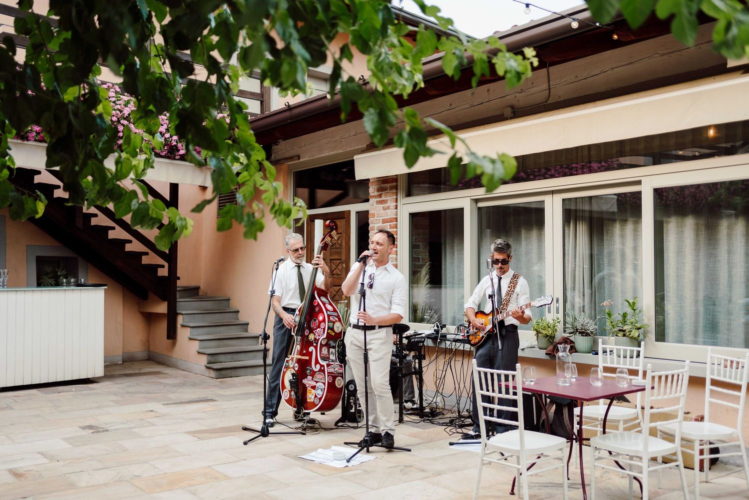 Outdoor jazz band performing on a patio with upright bass and guitar at a wedding venue.