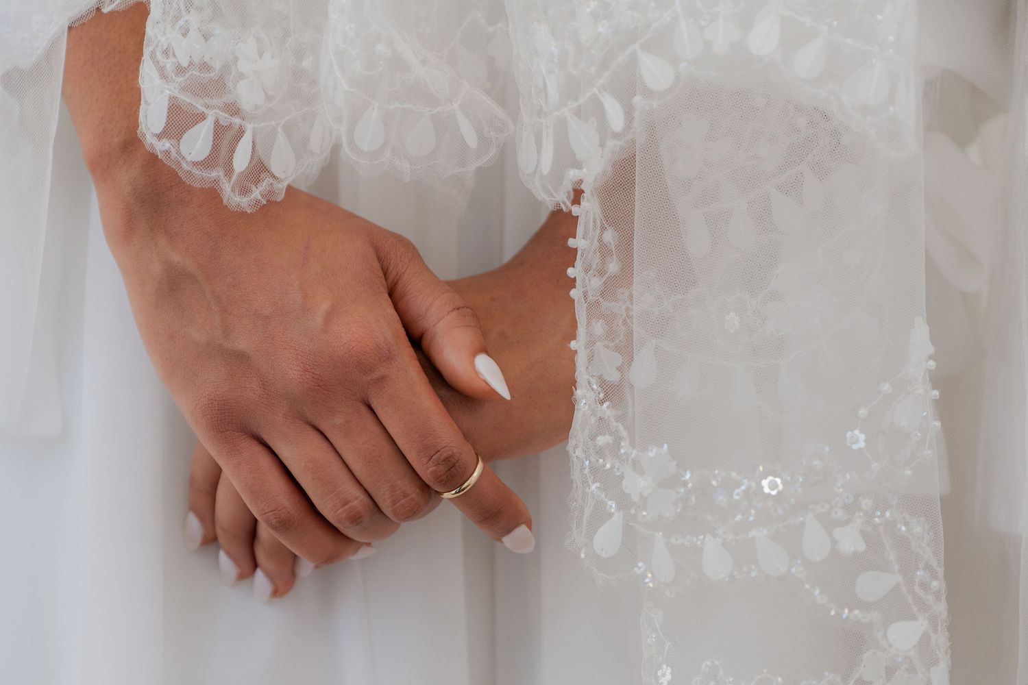 Detail of a bride's hands and lace sleeve at a Mansion at Tuckahoe wedding