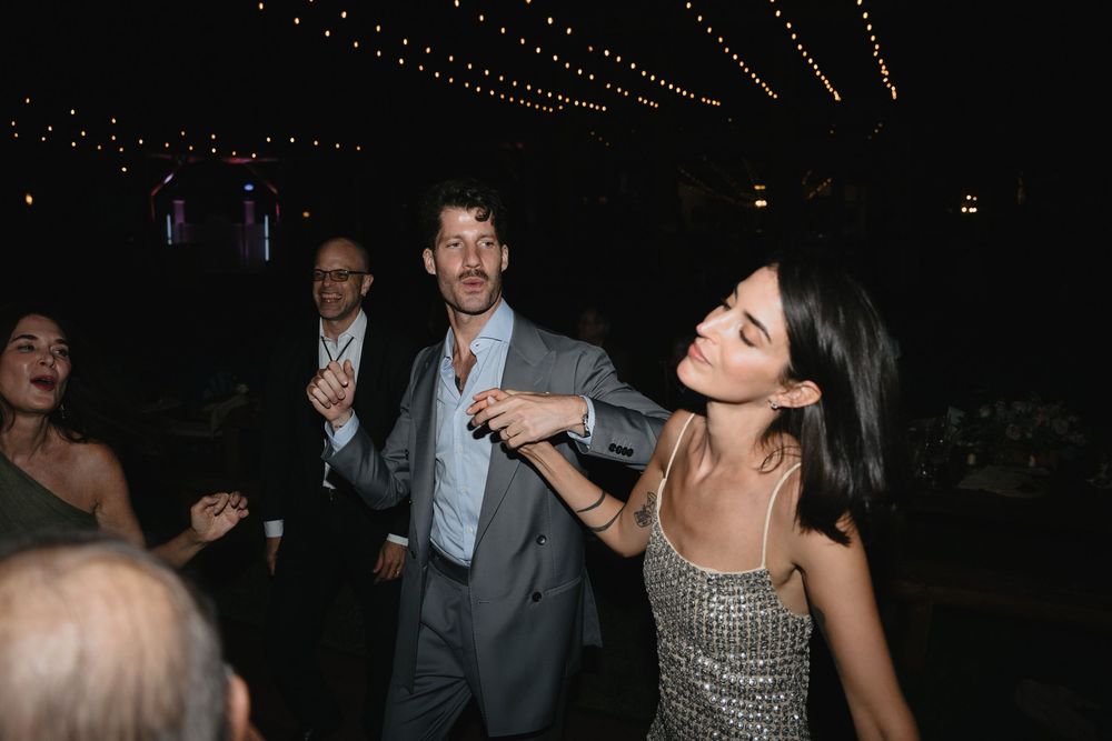 Couple dancing joyfully at an elegant evening event with string lights in the background.