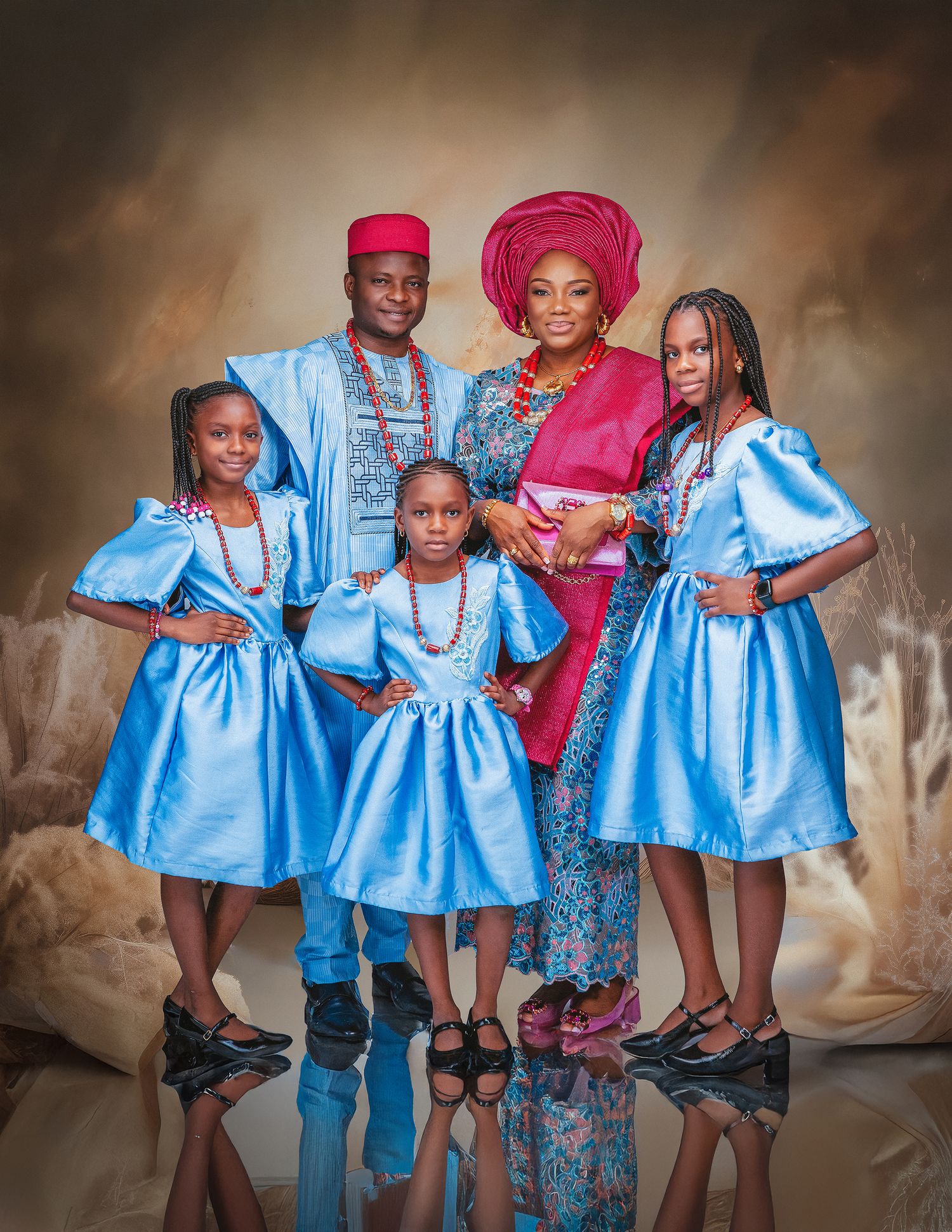 Nigerian family in traditional attire posing for a portrait, wearing blue outfits with red accessories.