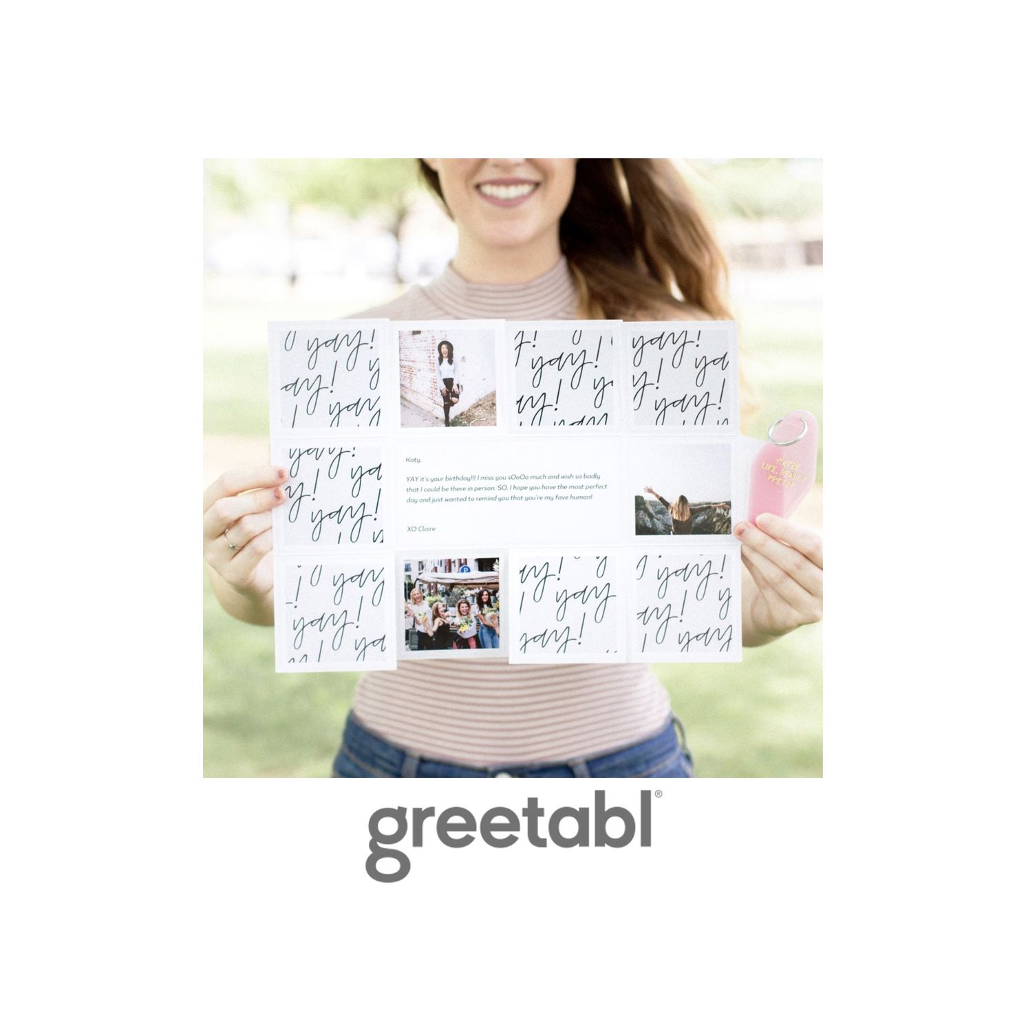 Woman holding a large Greetabl gift card with photos and cursive text, standing outdoors in a park.