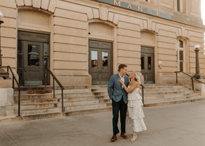 Couple sharing a romantic moment outside a historic brick building during an engagement photo session.