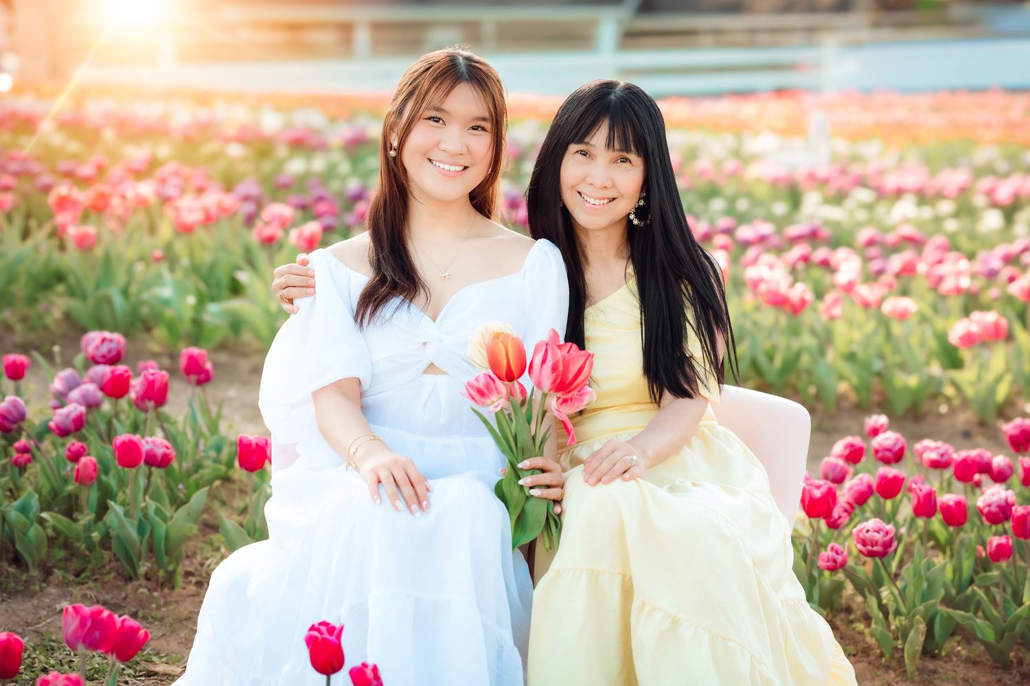 Family of five smiling together in a wildflower field at golden hour, wearing casual outfits in a warm outdoor setting.
