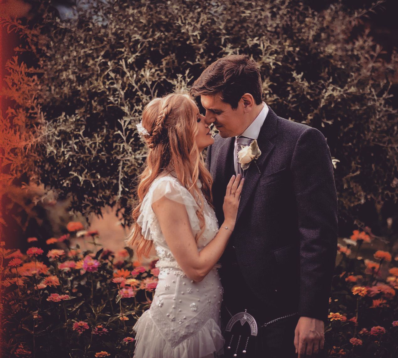Intimate wedding portrait among autumn foliage with warm reddish tones.