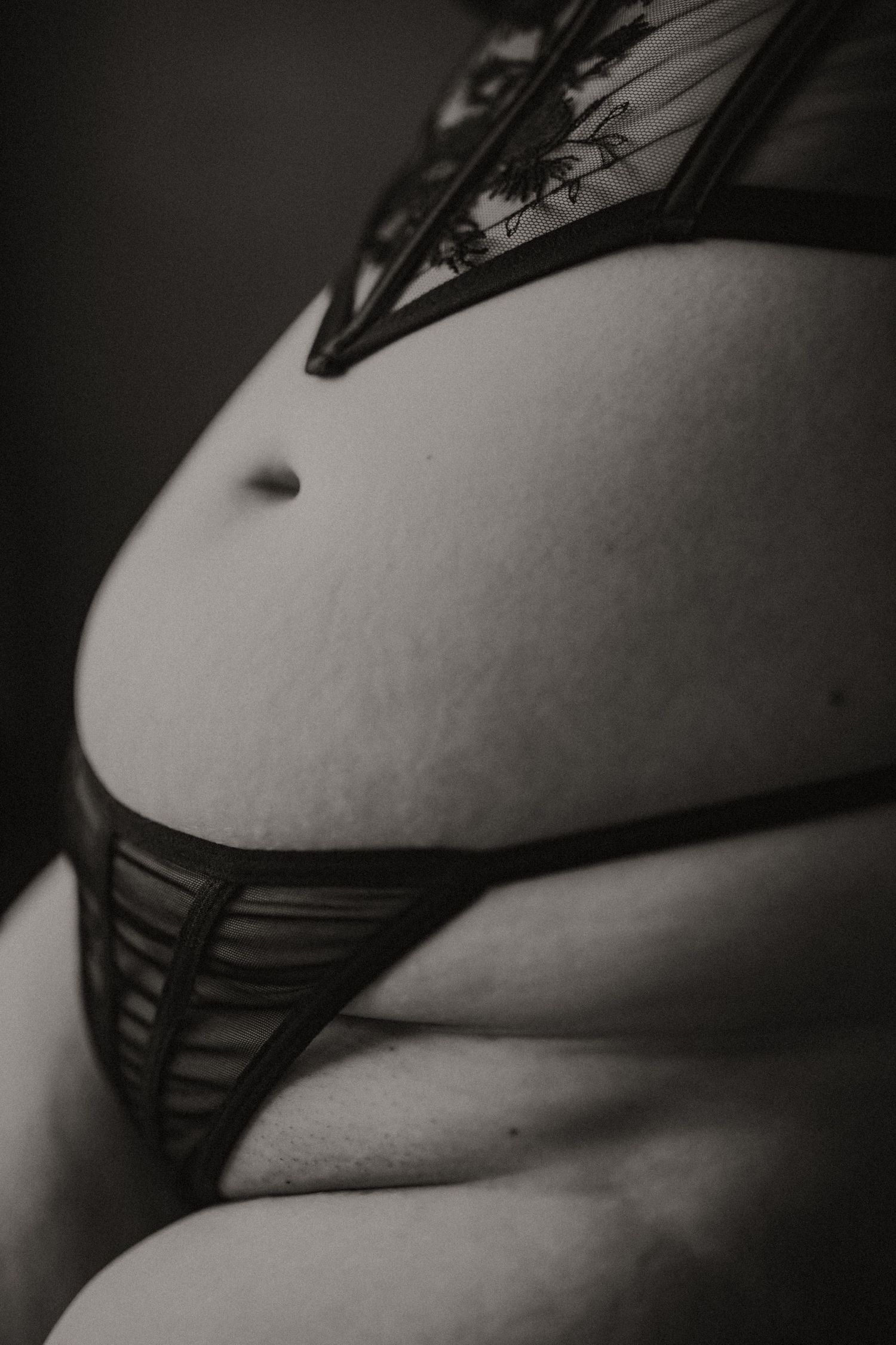 Black and white close-up of a woman's midsection wearing decorative black lingerie.