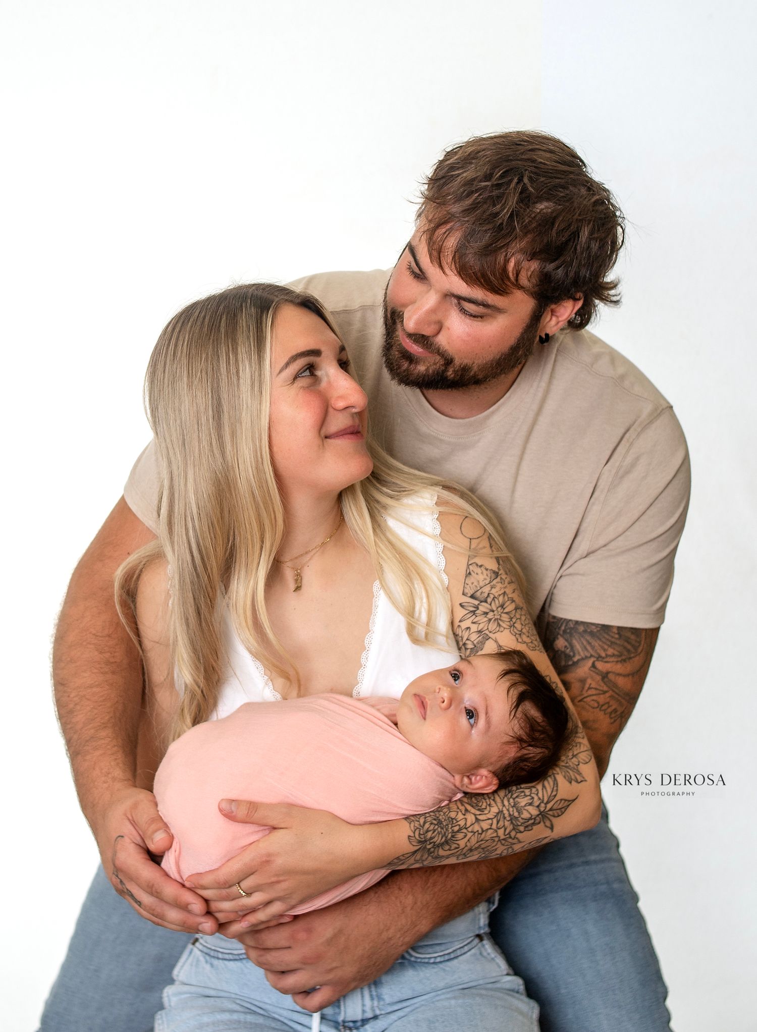 Black and white newborn photography showing tiny sleeping baby cradled in parents hands against dark background.