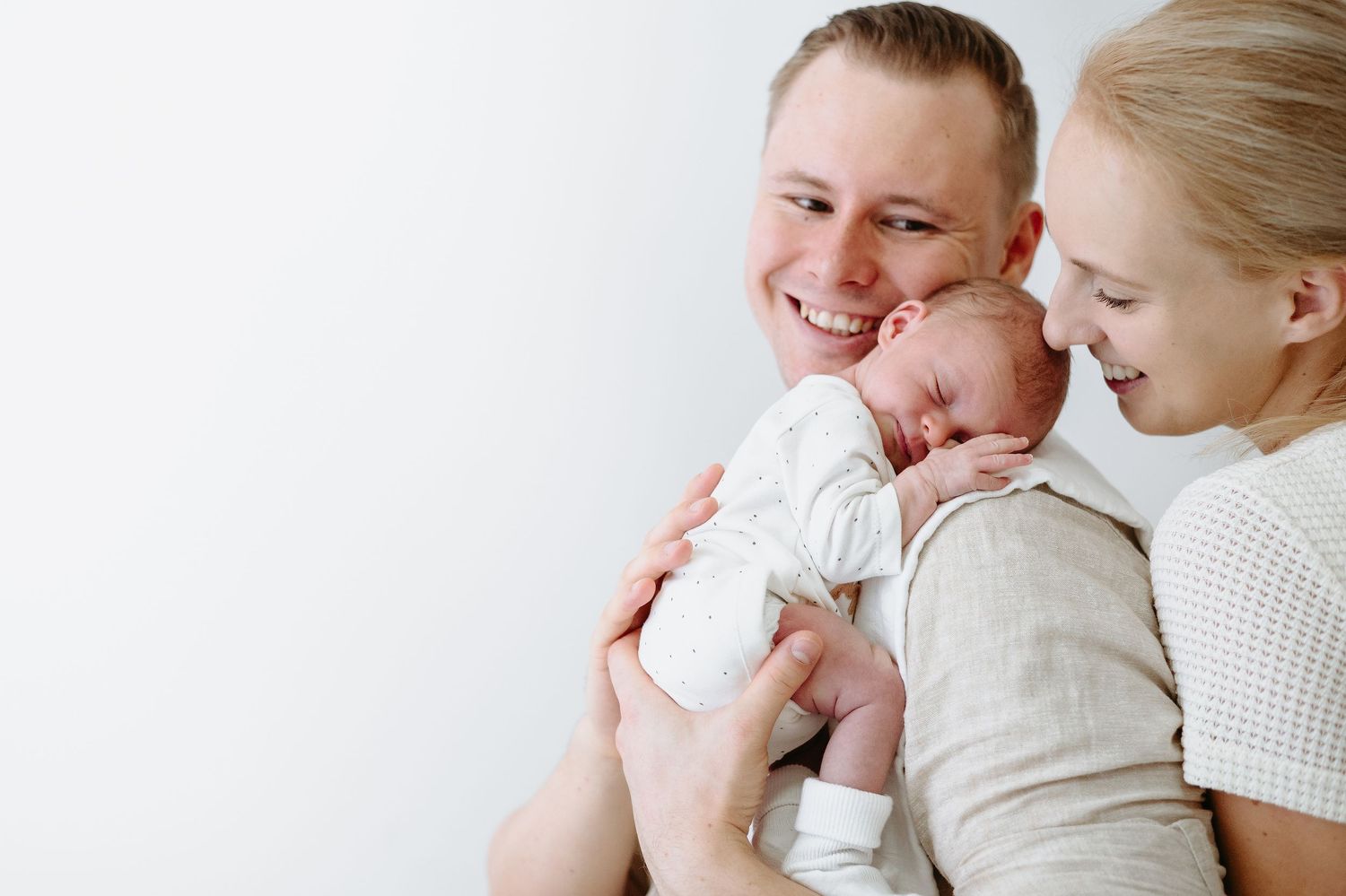 Dark and moody family portrait with newborn baby in dramatic lighting.