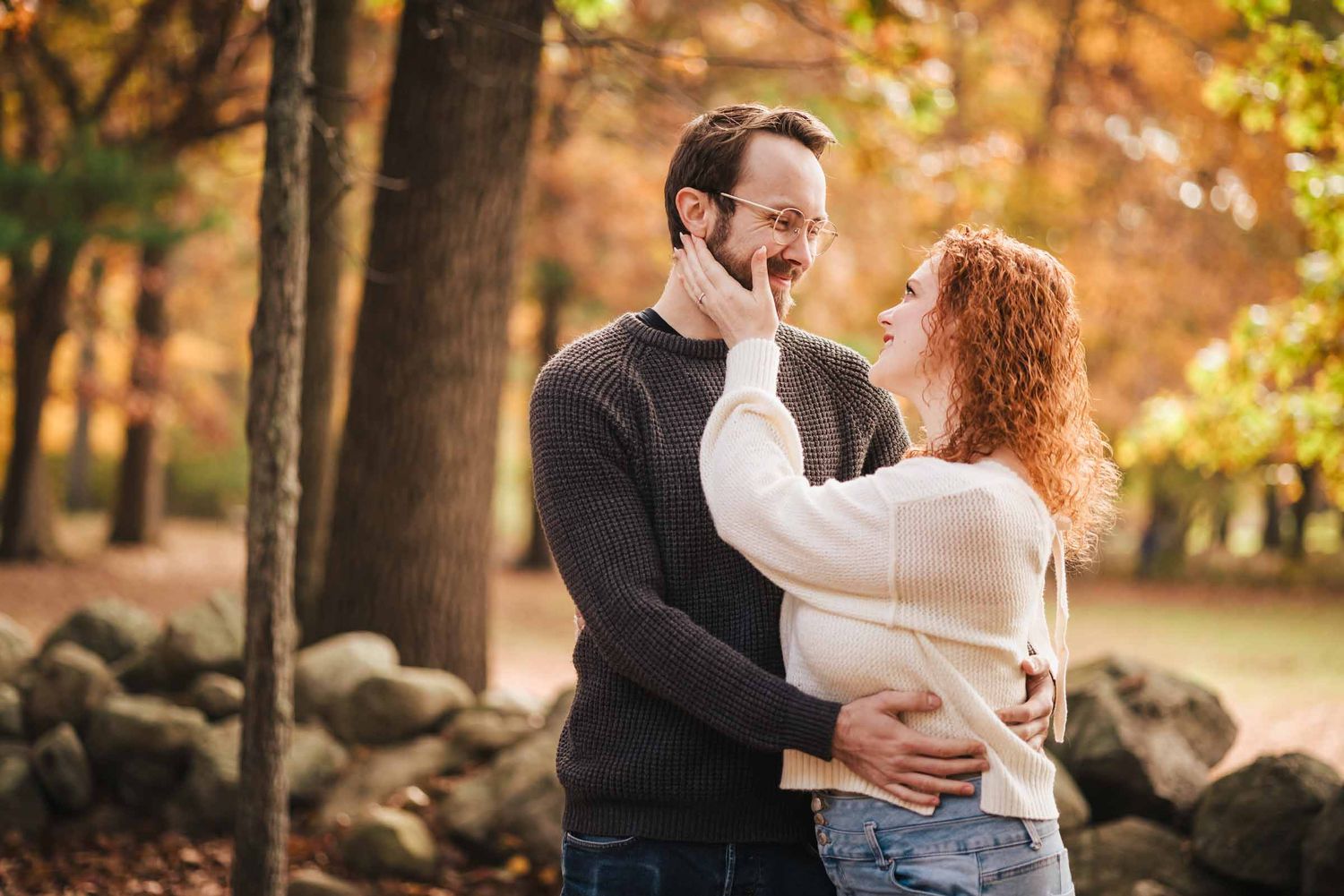 Engaged couple sharing a close moment on a wooded trail at Borderland State Park, surrounded by warm autumn light.