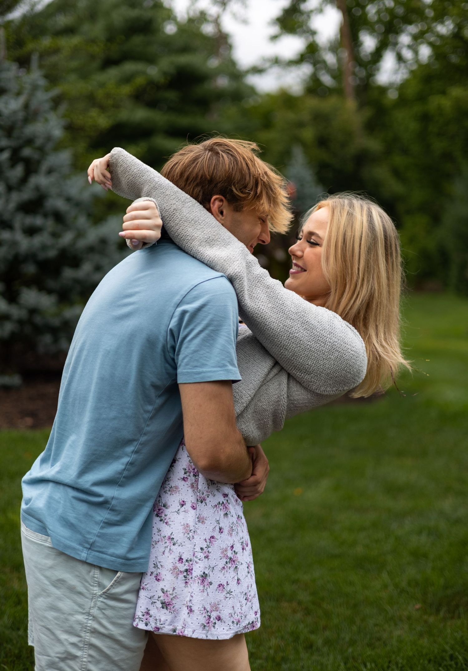 Happy young couple hugging and laughing together outdoors in a green park setting.