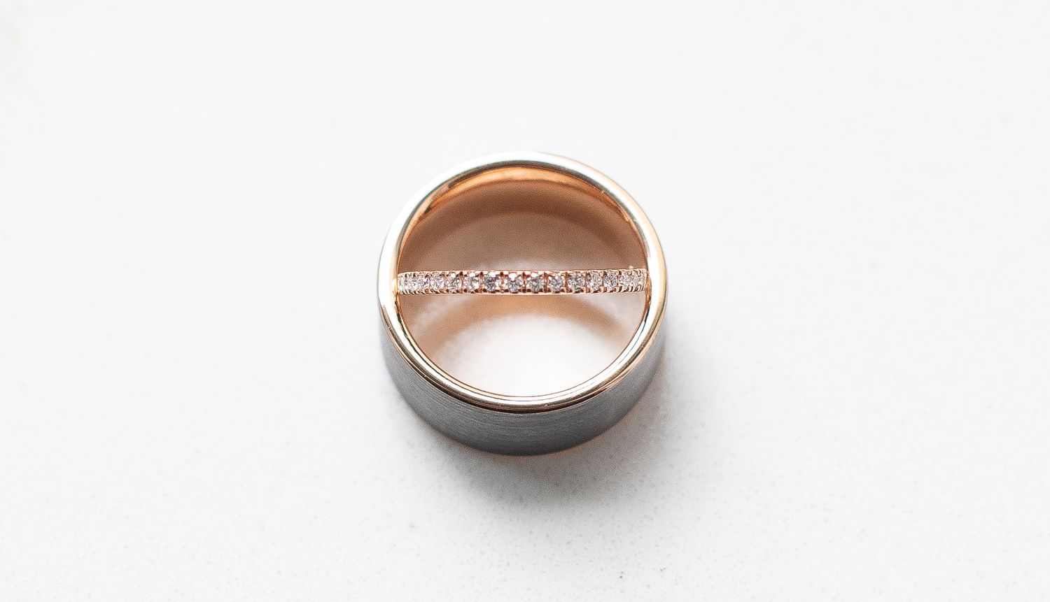 Two-tone rose gold and silver diamond band ring displayed on white background.