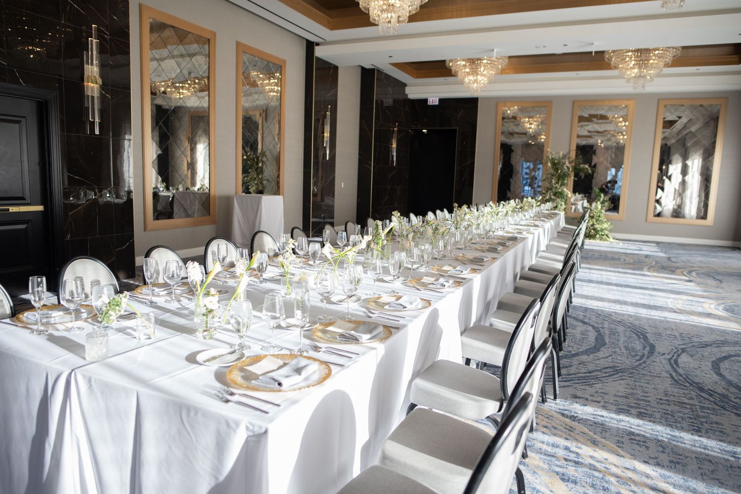 Elegant wedding reception banquet table with white linens, crystal glasses, and floral centerpieces.