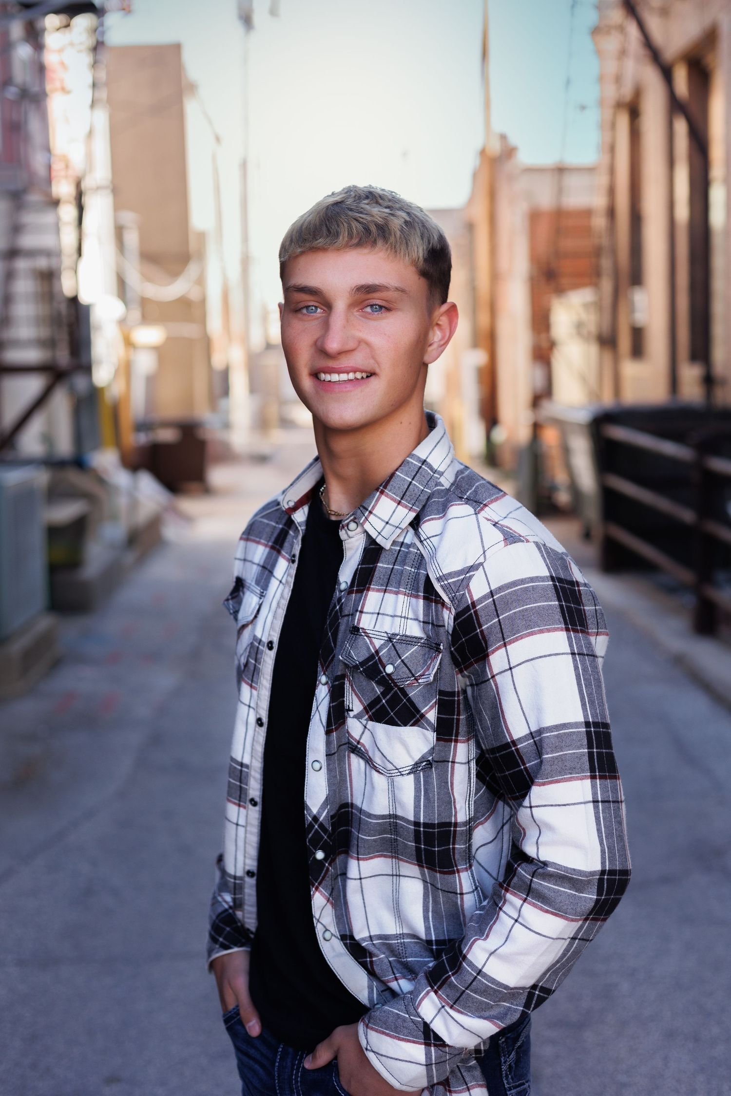 Portrait of youth wearing plaid shirt and jeans in urban alley.