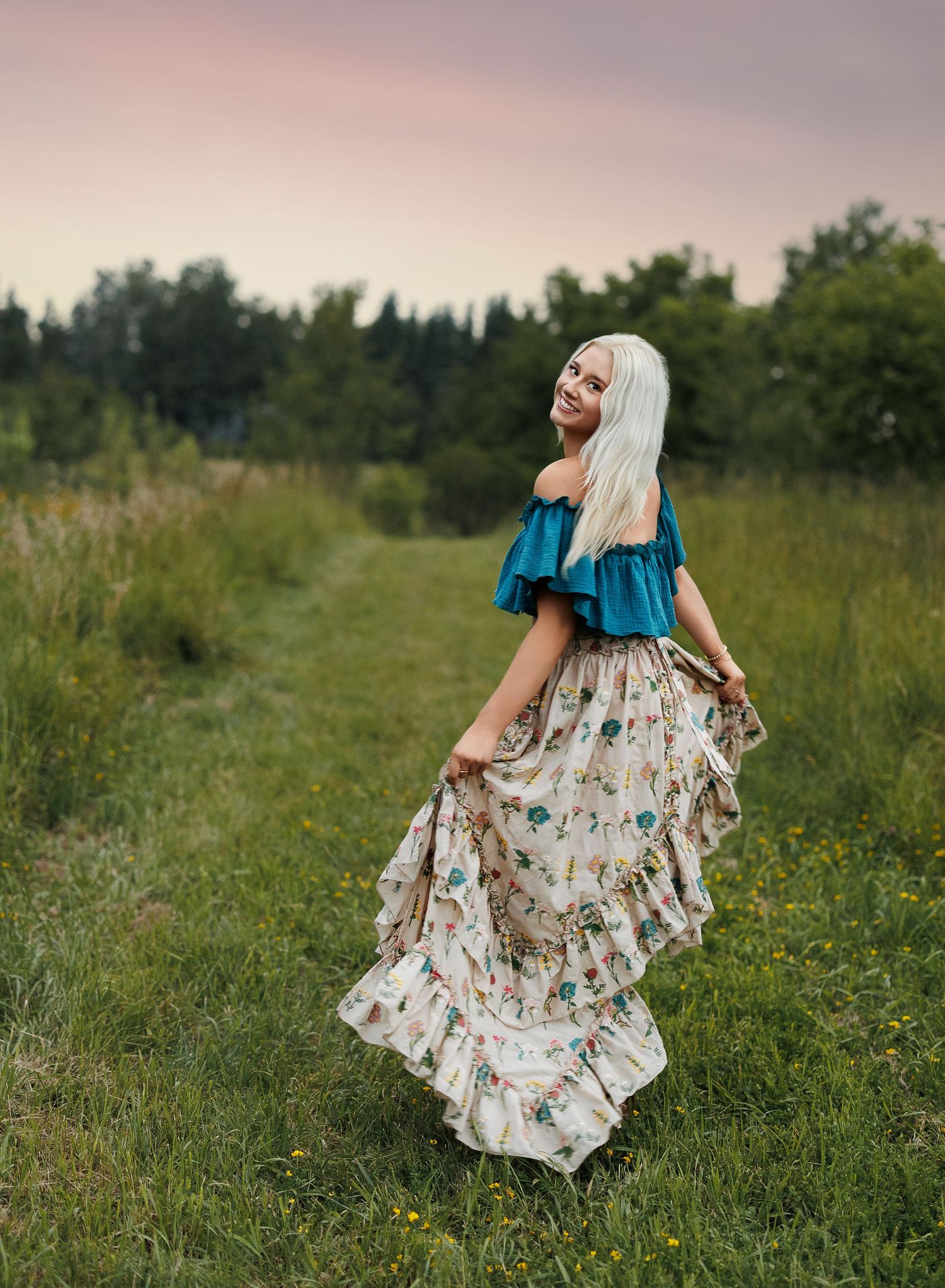 A floral dress flows gracefully through a summer meadow as a senior twirls in the golden afternoon light.