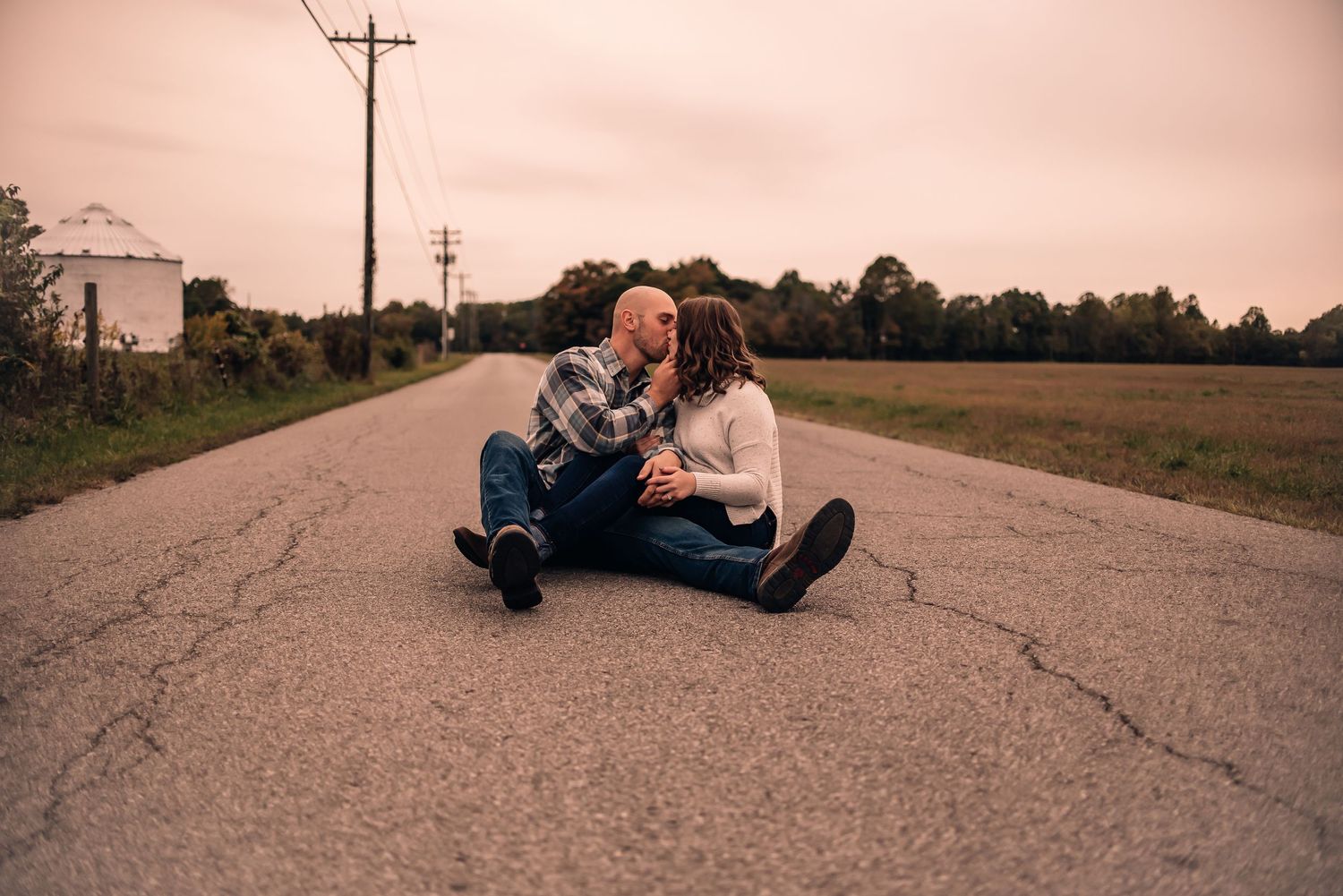Sunset silhouettes captured in a romantic sequence of poses on a rural road.