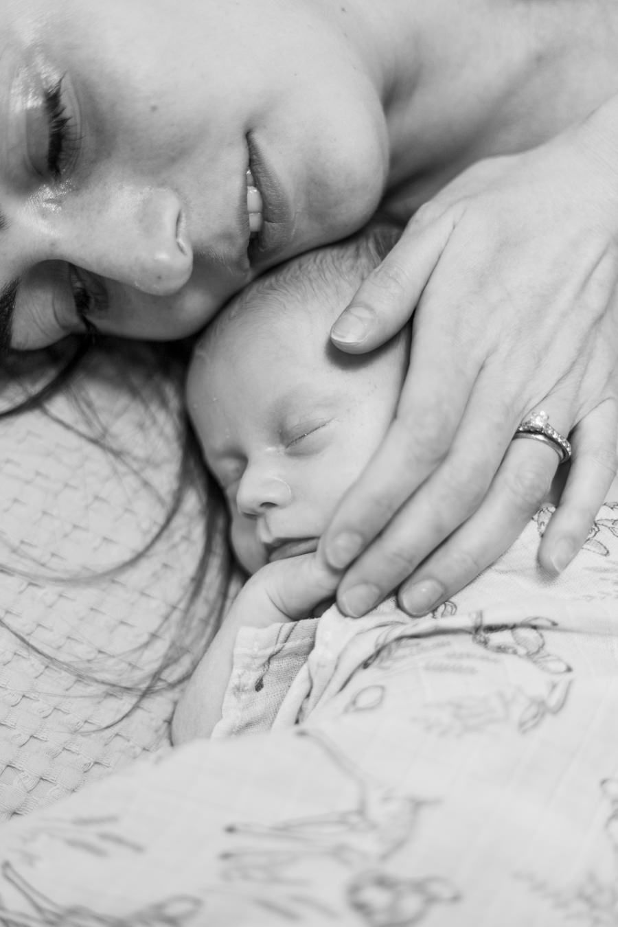 An intimate black and white close-up of parent and sleeping baby sharing a tender moment.