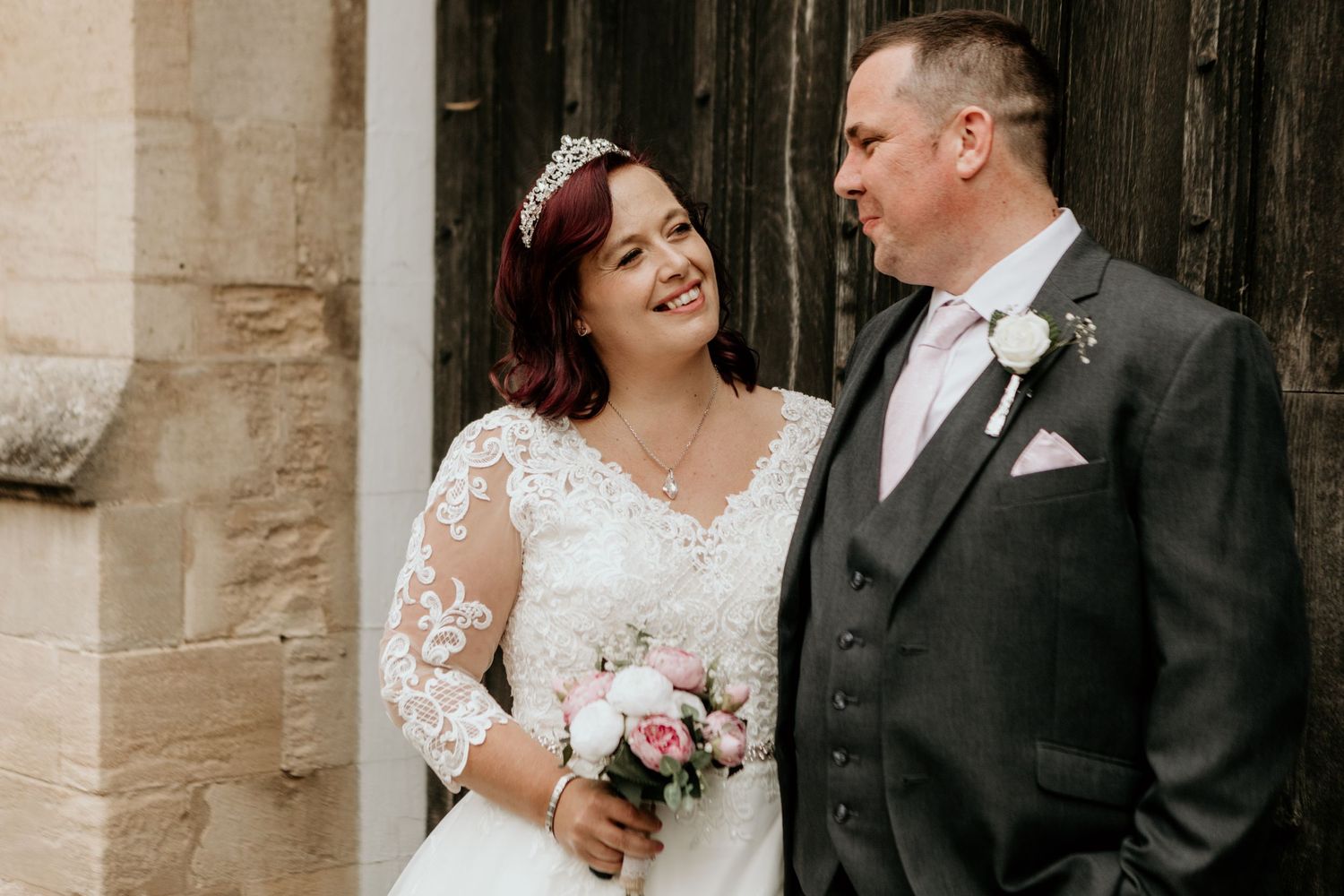 bride and groom stood in front of stone walls and door