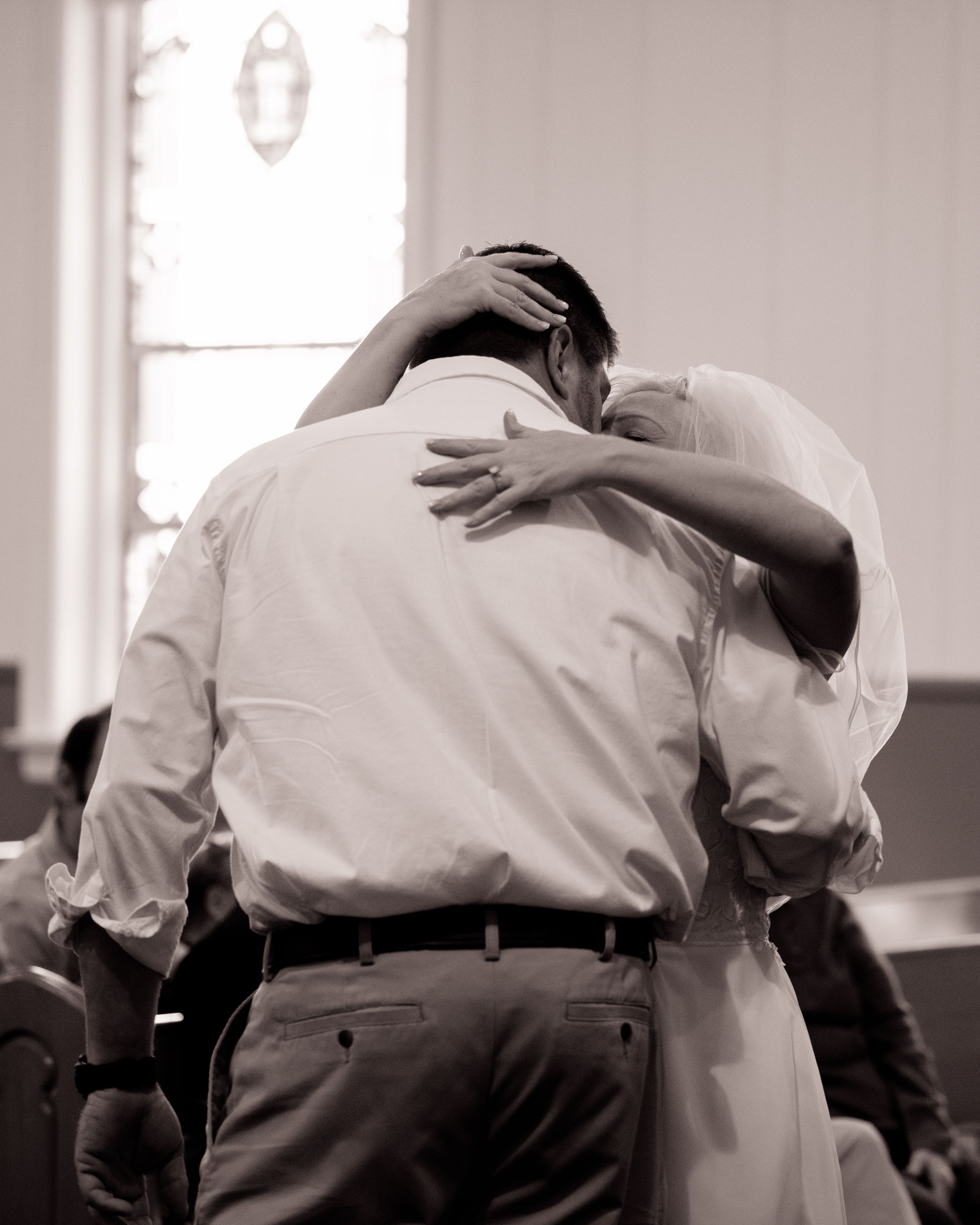 A romantic black and white photograph shows an intimate embrace between a bride and groom.