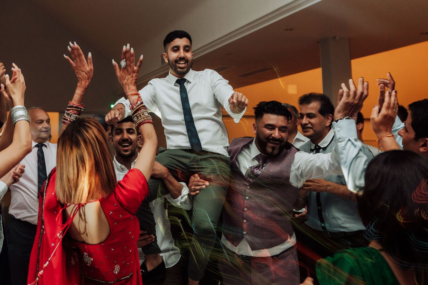 Energetic wedding reception dance party with guests jumping and celebrating.