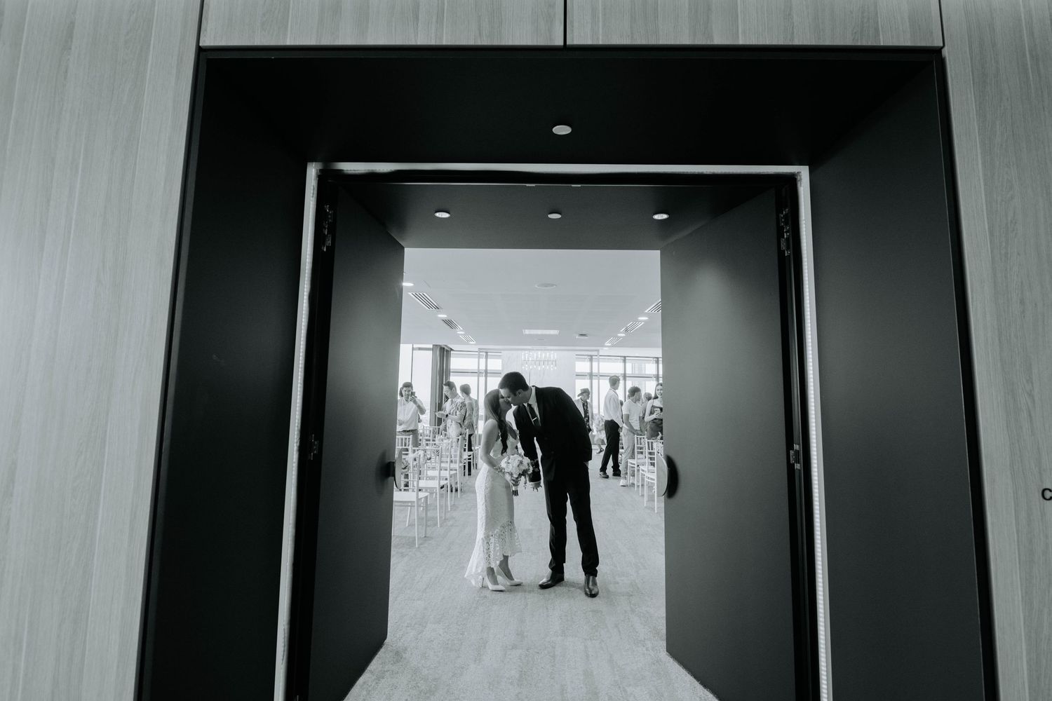 Black and white wedding photo of couple silhouetted in doorway.