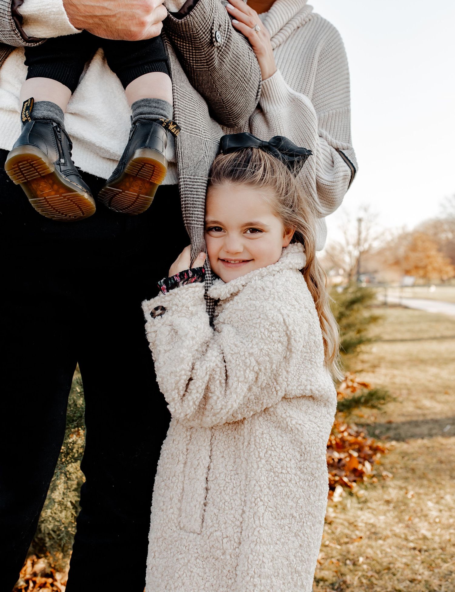 A young child in a cozy sherpa coat smiles warmly at the camera during an autumn photoshoot.