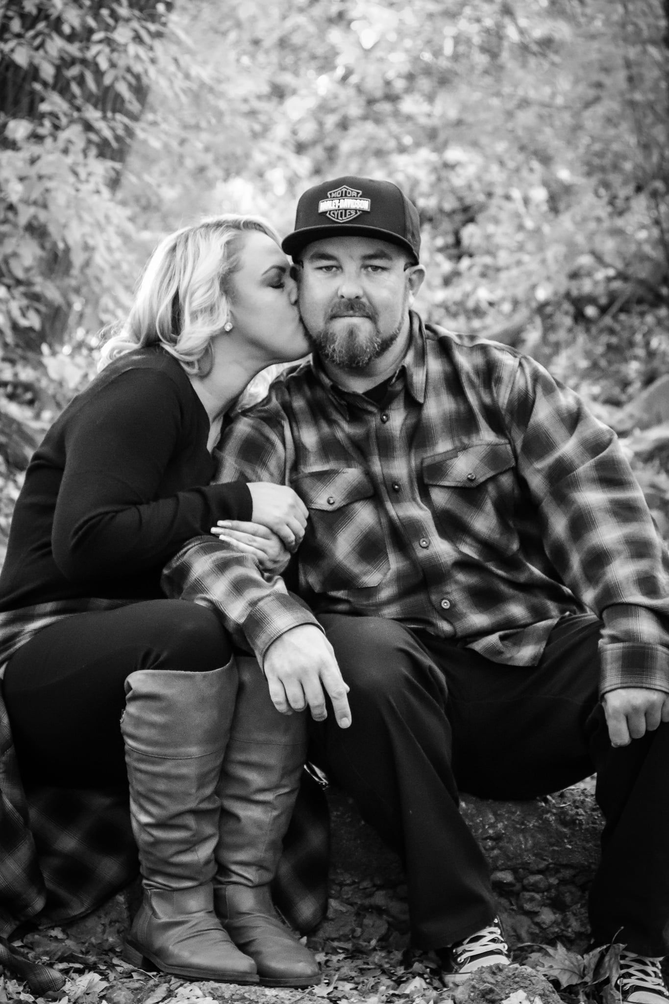 Romantic black and white portrait of affectionate couple sitting outdoors together.