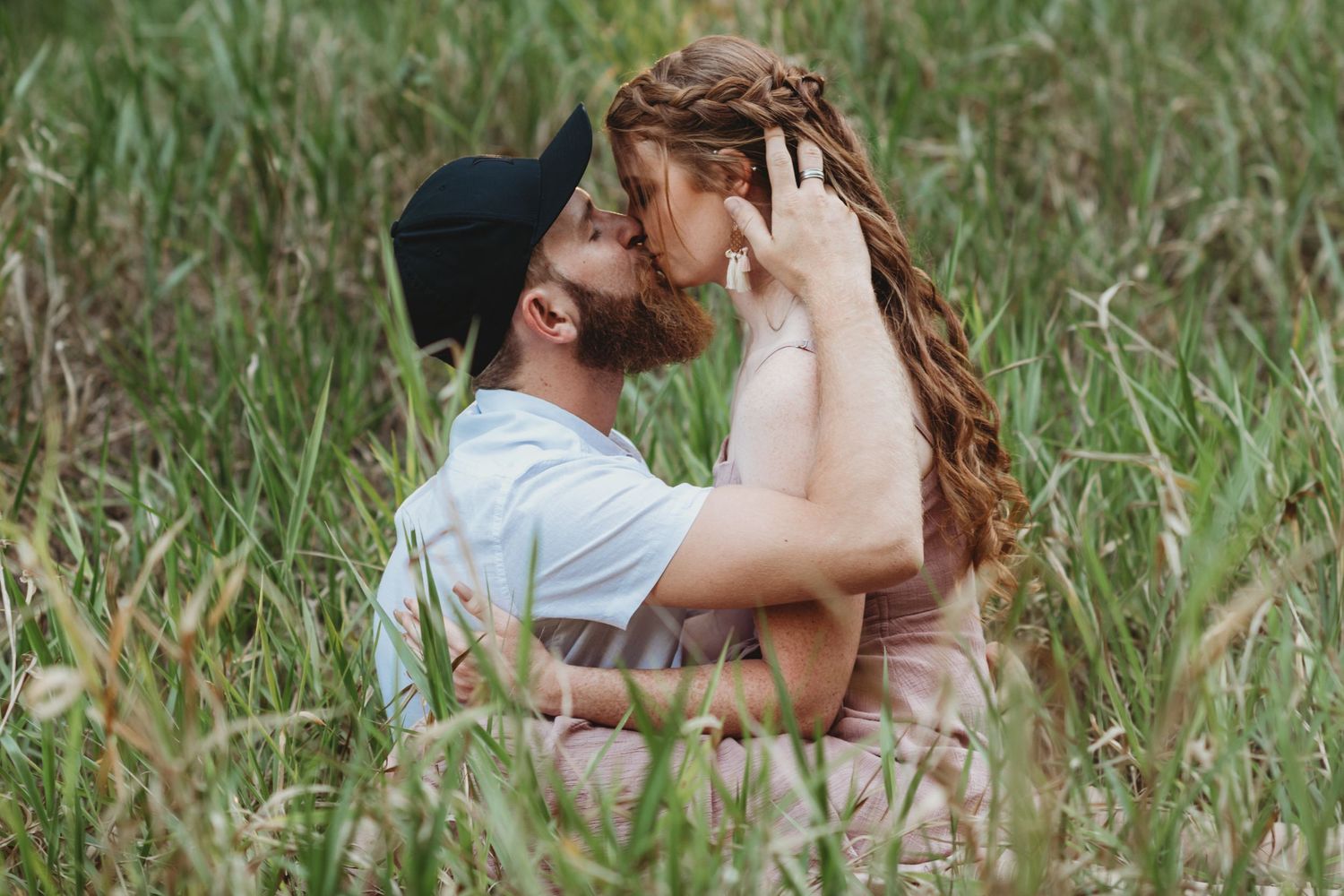 Intimate moment shared between couple in tall summer grass field.