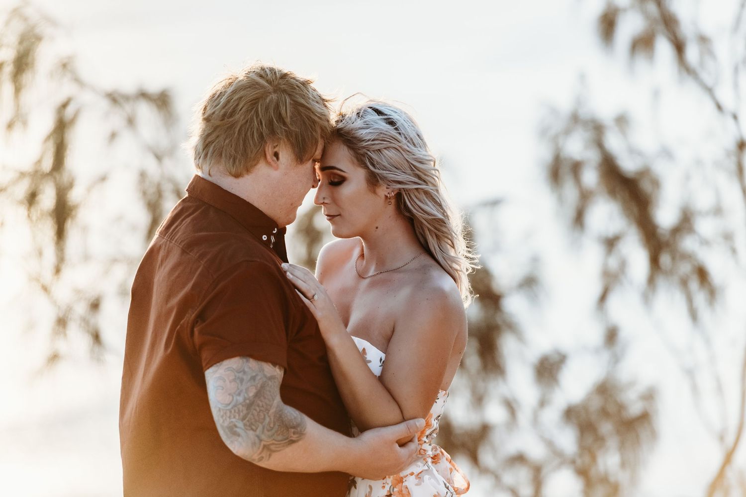Romantic moment captured during golden hour with soft lighting and Spanish moss in background.