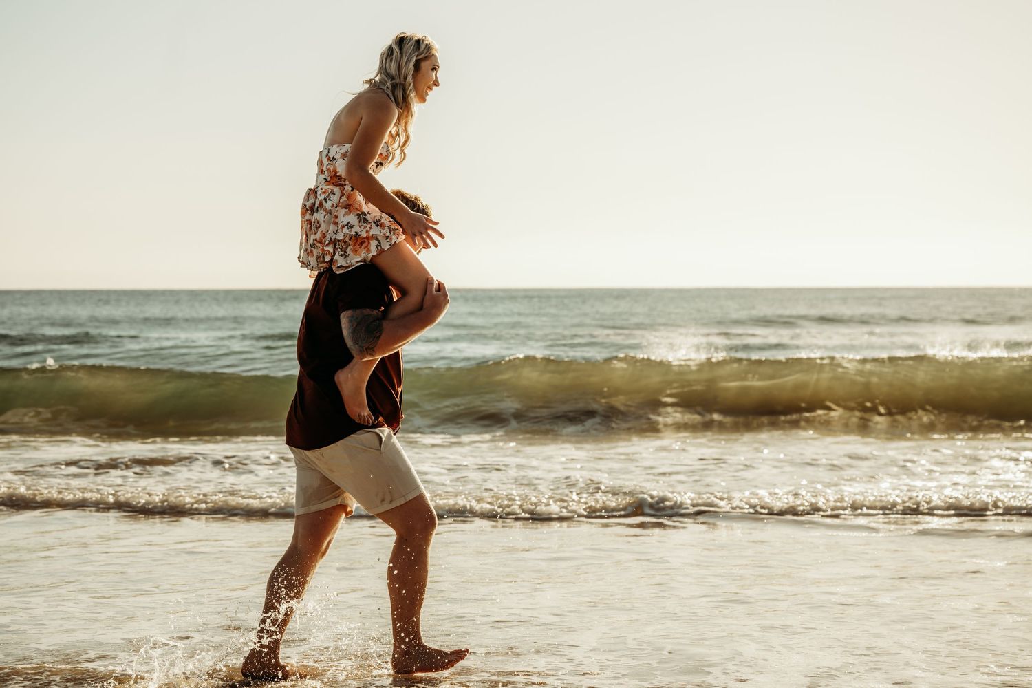 A playful lift on the beach at sunset with ocean waves in the background.