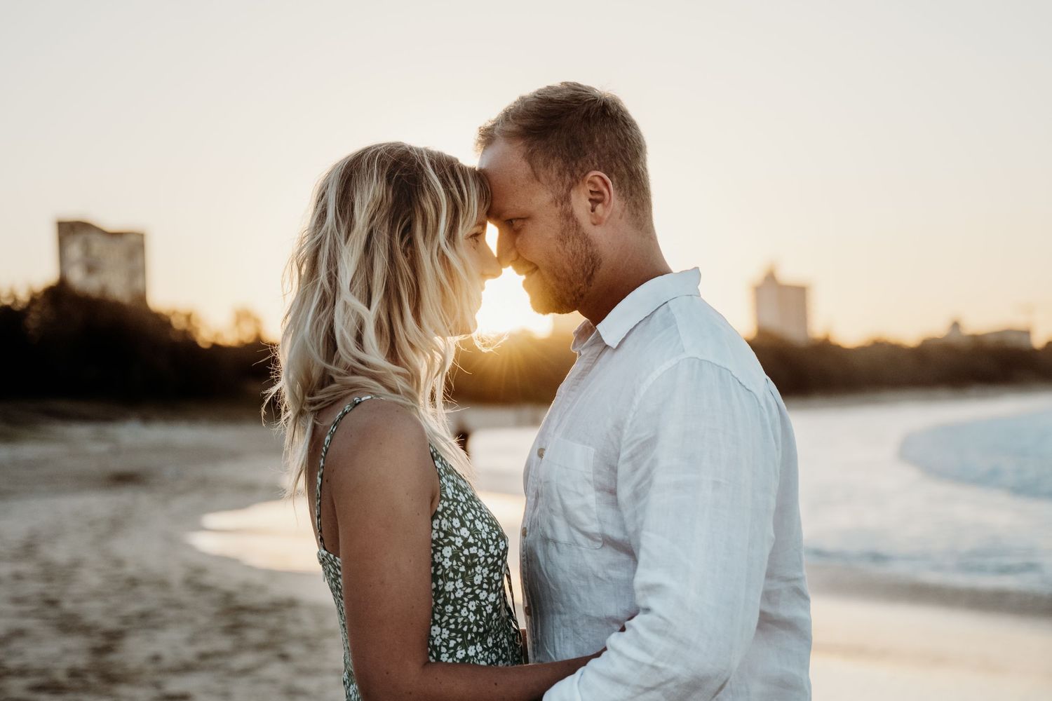 A tender moment between a couple on the beach at sunset.