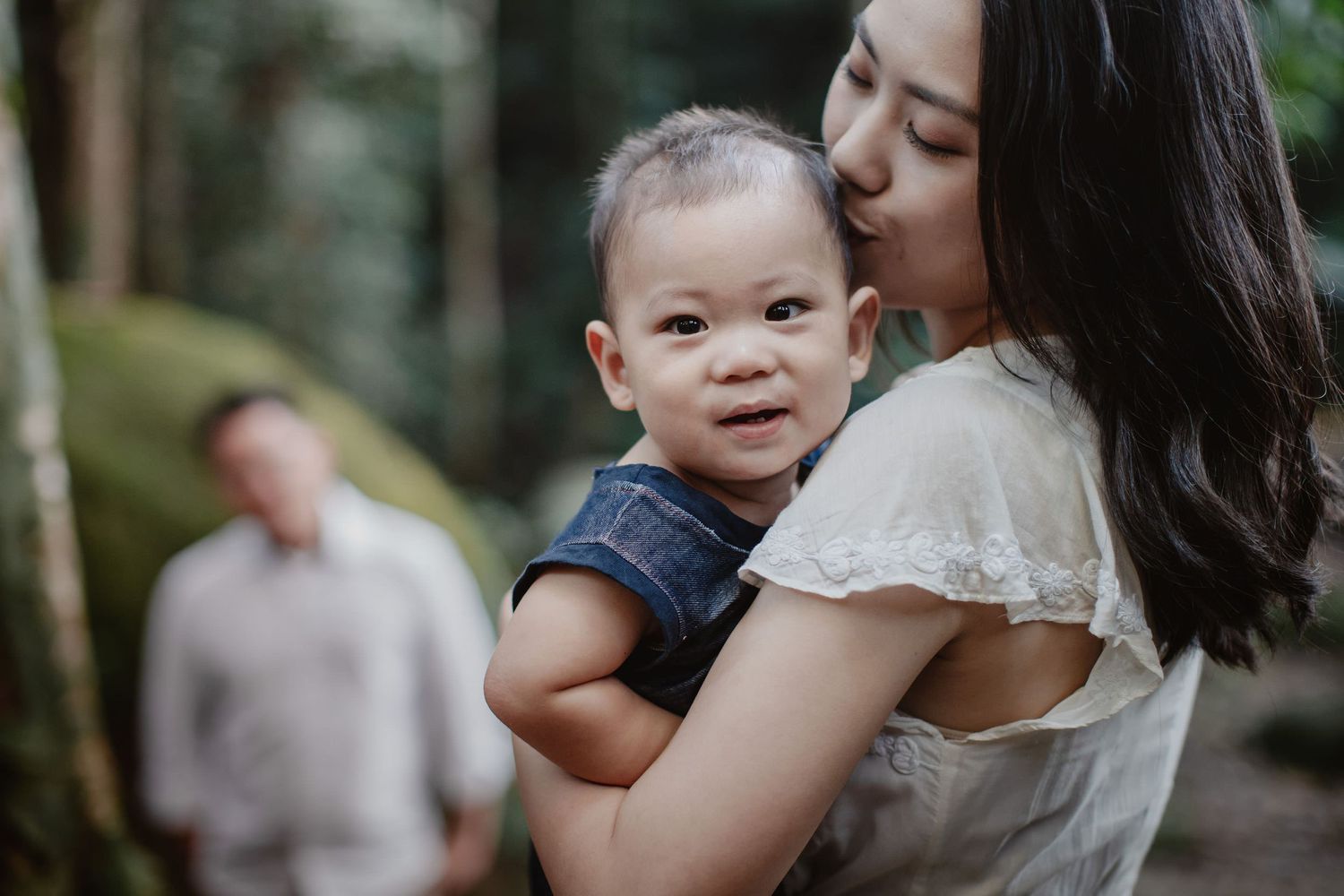 mother kissing her happy boy with father behind in the FRIM
