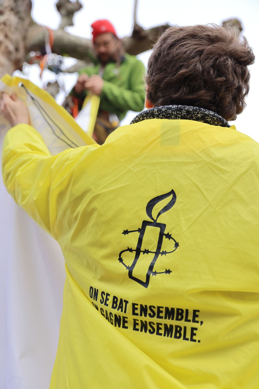 Yellow jacket with Amnesty International logo and French text worn by event participant.