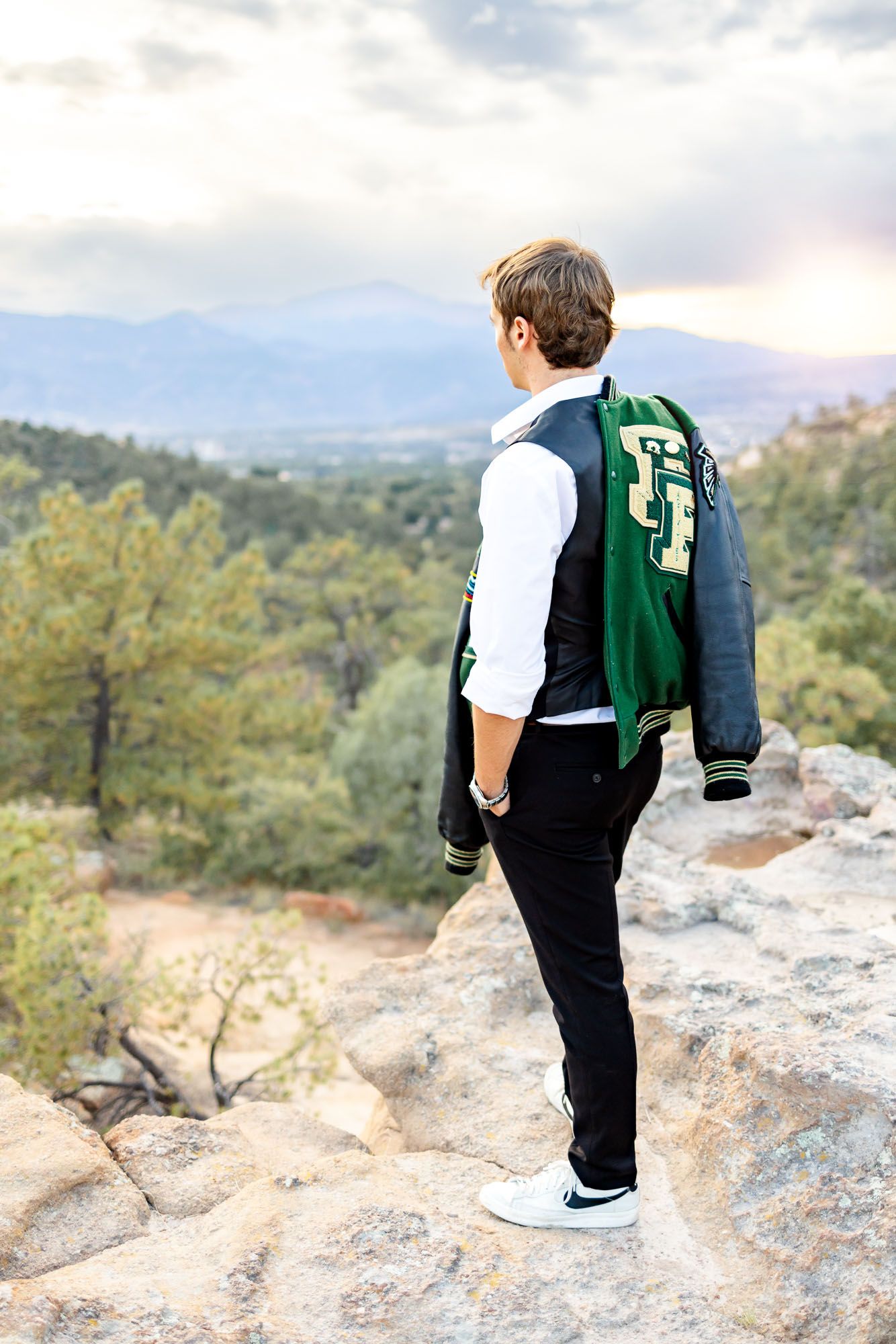 Senior guy poses with his letter jacket over his shoulder at his senior session at Palmer Park in Colorado Springs.